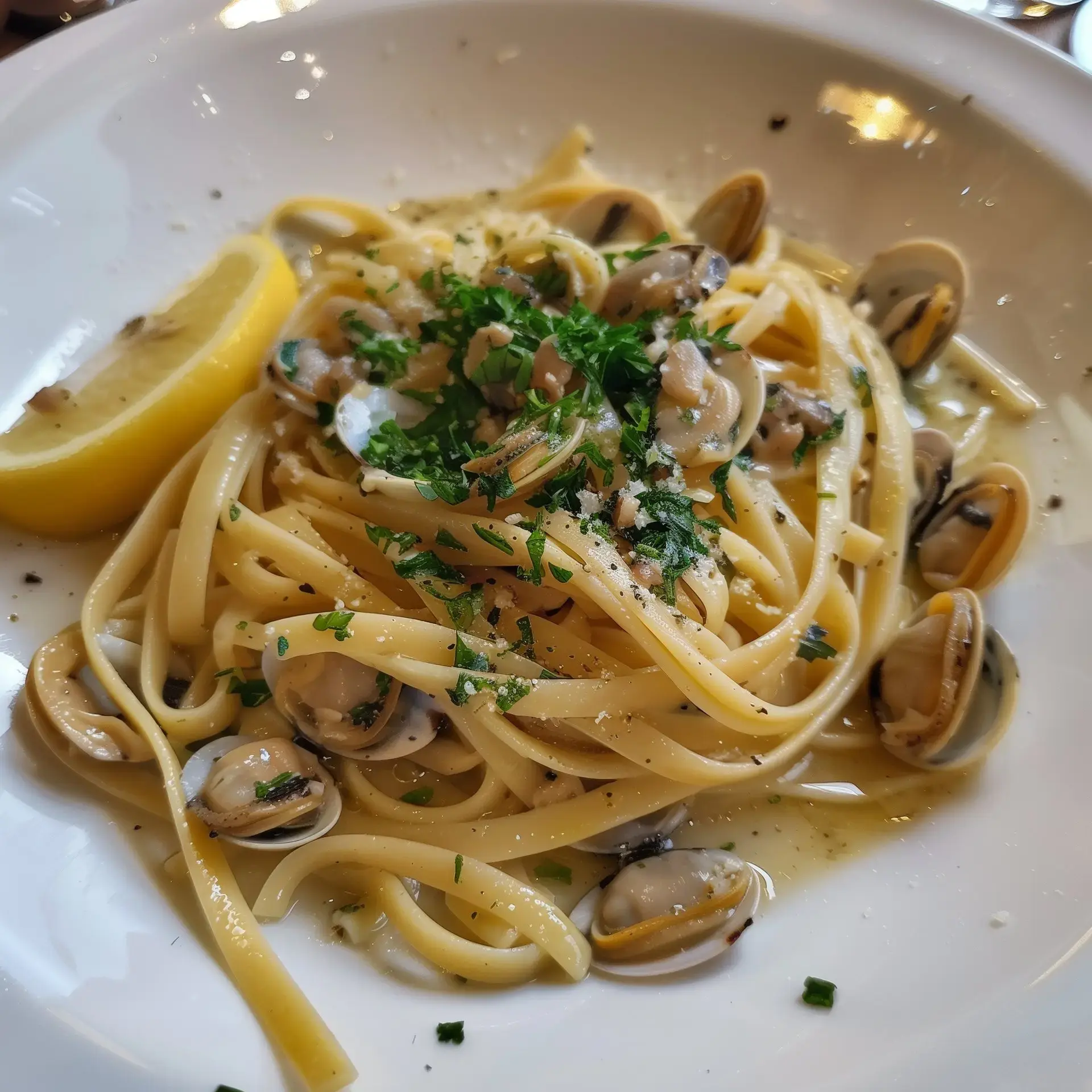 Italienische Pasta mit Muscheln, Petersilie und Zitronenscheibe dekoriert.