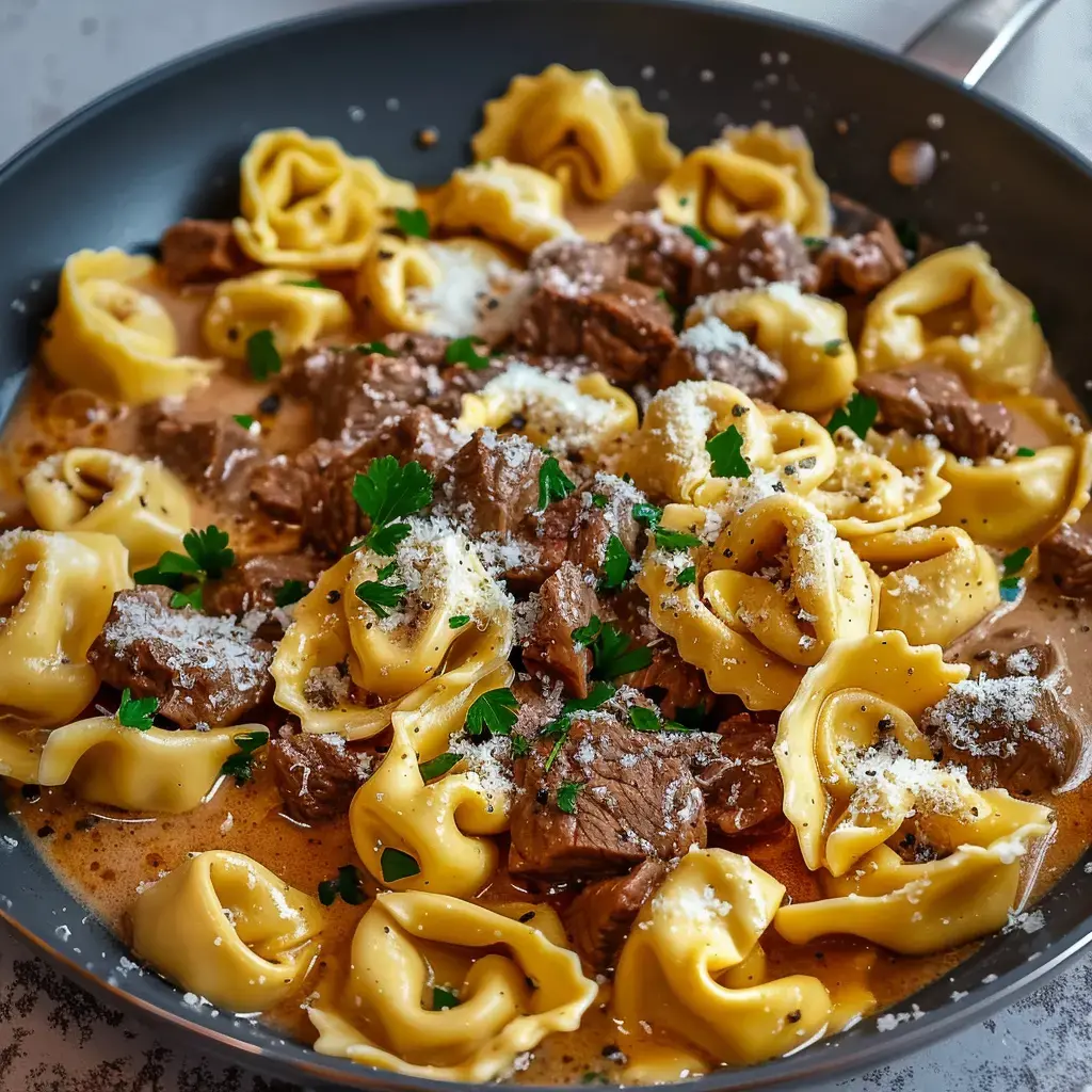 Eine cremige Tortellini-Pasta mit zartem Rindfleisch, garniert mit Parmesan und Petersilie.