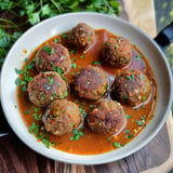 Azuki-Bohnen-Bällchen in einer würzigen Tomatensauce, garniert mit Koriander.